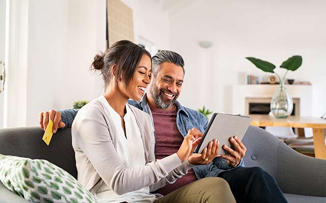 Couple on the couch using a tablet to do their banking