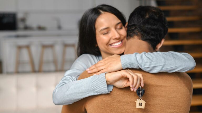 Woman embraces man holding a key with a house keychain