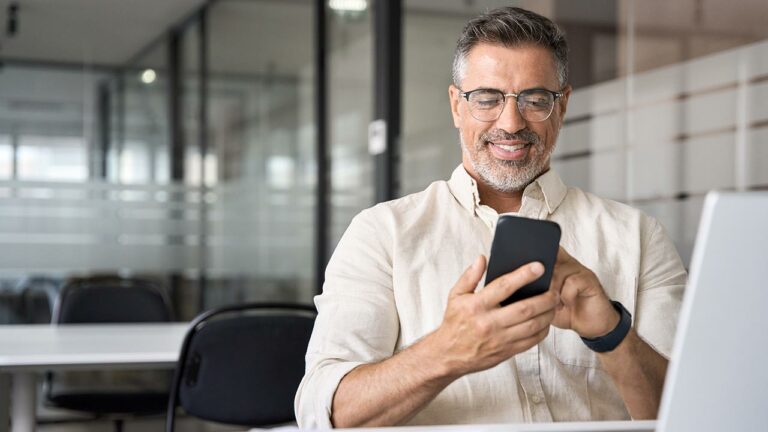 Man smiling as he uses a smart phone