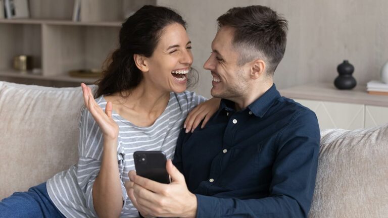 Couple smiling as they look at their phone