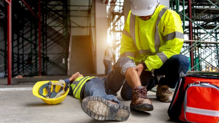 Construction worker helping a co-worker who hurt his leg